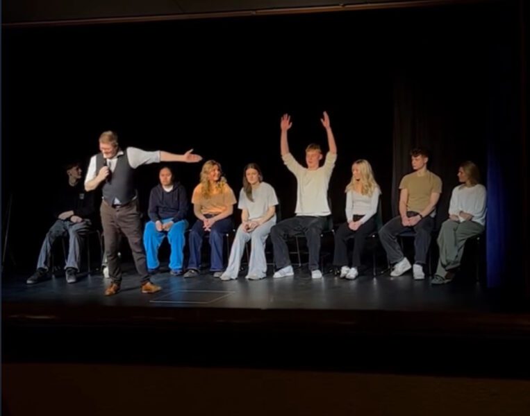 This picture shows Lasse Kvist with a number of students seated behind him. The story behind it is that he mentions a name; in this case it was 'Magnus'. As he said it, Magnus covered both hands in the air, due to hypnosis. He then thanks Ranum Efterskole for the opportunity to present a fantastic show.